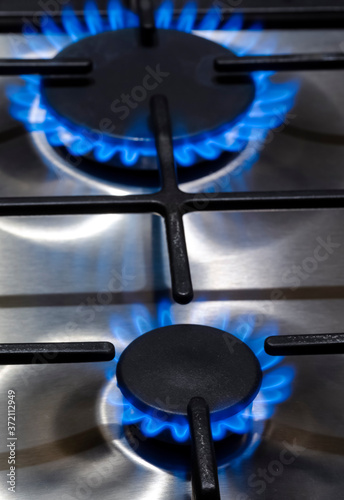Gas Concepts. Closeup Macro Shoot of Two Gas Burners on Stove Surface with Fire Flames.