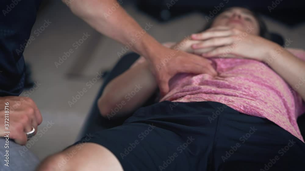 Massage therapist pressing on torso of patient laying on table close up pull away physical therapy doctor's office Massage therapist pressing on torso of patient laying on table close up pull away physical therapy doctor's office
