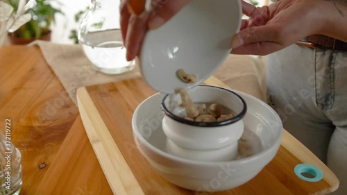 Woman washing cashews for making milk photo