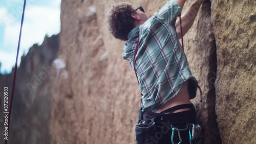 Back shot of young teen rock climber reaching to the next hold photo