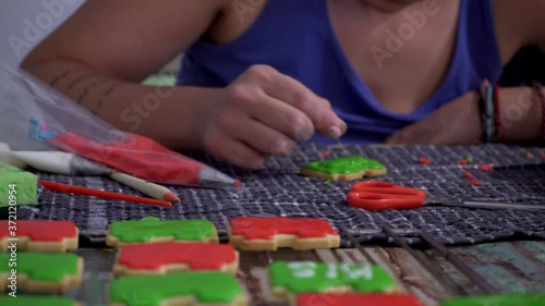 Caucasian woman decorating brick shaped cookies with sugar icing. Front view, shallow depth of field 4k photo
