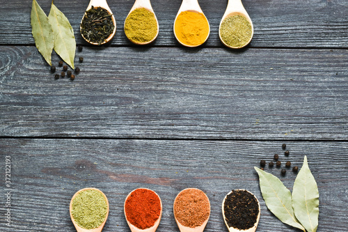 Herbs and spices in wooden spoons on a wooden background. Cooking, gardening or vegetarian concept. Copy space, flat lay,top view.