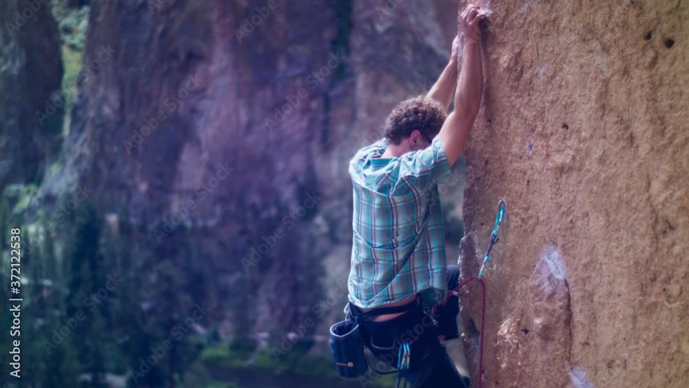 Young climber in vertical Smith Rock arete clipping rope in carabiner Young climber in vertical Smith Rock arete clipping rope in carabiner
