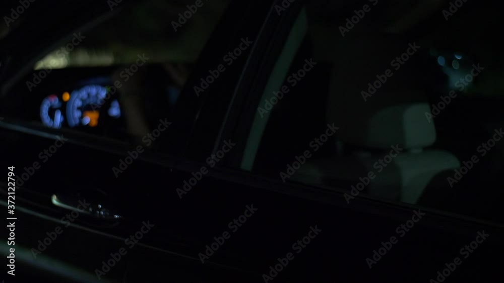 Caucasian male with hands on the steering wheel, as law enforcement approaches the black vehicle, during a night time traffic stop. Slowed to half speed Caucasian male with hands on the steering wheel, as law enforcement approaches the black vehicle, during a night time traffic stop. Slowed to half speed