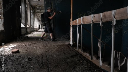 a young researcher in a hat and with a backpack climbs the stairs and passes into the hall of an abandoned factory. dangerous railing fenced with tape photo