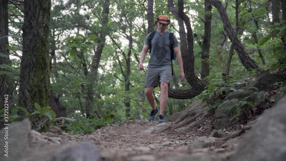 Low angle view of male swet tired hiker walking down from the mountain trail Low angle view of male swet tired hiker walking down from the mountain trail