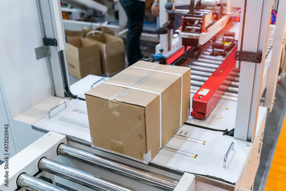 cardboard box of product packaging is moving on conveyor belt of automatic  packing machine in the manufacturing factory Photos | Adobe Stock