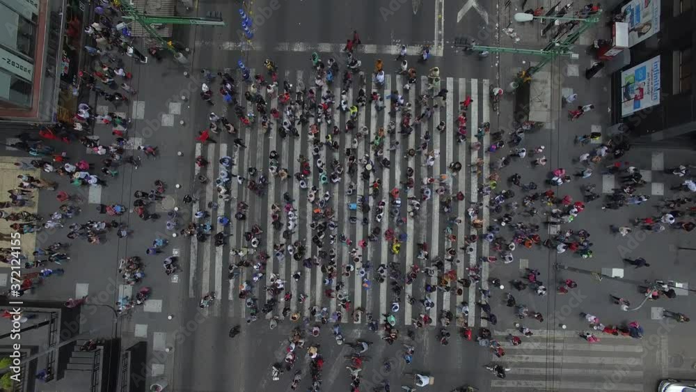 Vista aérea cenital de una multitud caminando sobre el cruce peatonal más transitado de México. El drone elevándose lentamente mientras la gente cruza Eje Central