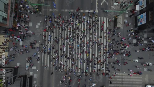 Vista aérea cenital de una multitud caminando sobre el cruce peatonal más transitado de México. El drone elevándose lentamente mientras la gente cruza Eje Central