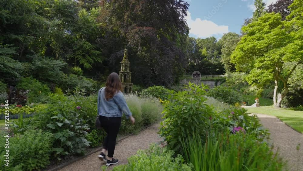 Woman walking in a beautiful and colorful garden during a blue sky day Woman walking in a beautiful and colorful garden during a blue sky day