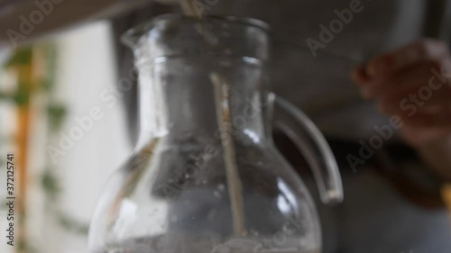 Woman Pouring Cashew Milk into a glass bottle photo