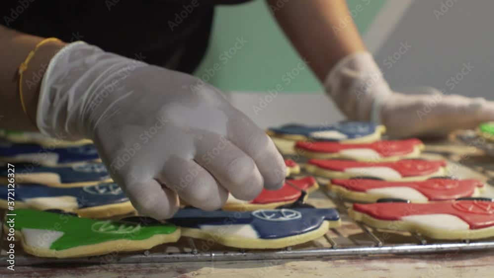 Woman decorates homemade vehicle shaped cookies with sugar icing. Slide shot close up on hands Woman decorates homemade vehicle shaped cookies with sugar icing. Slide shot close up on hands