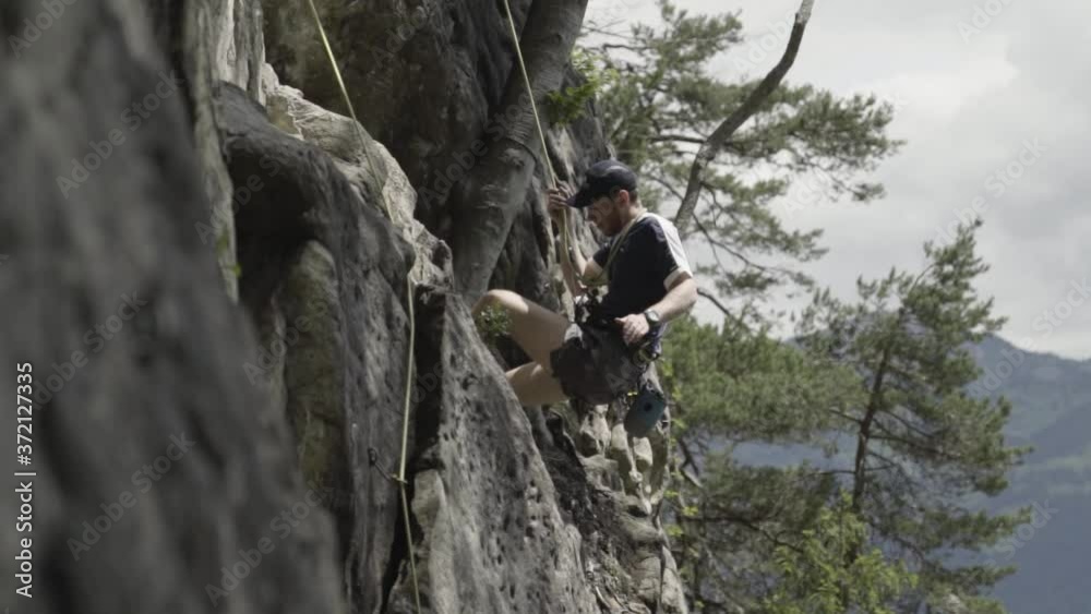 Climber Descending And Rappelling Down The Rocky Cliff Of Bockstor Near The Interlaken, Switzerland. -wide shot Climber Descending And Rappelling Down The Rocky Cliff Of Bockstor Near The Interlaken, Switzerland. -wide shot