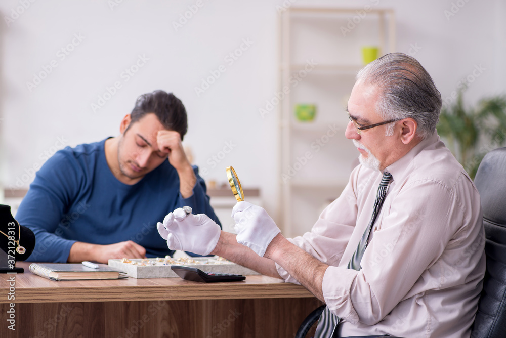 Young man visiting old male jeweler Young man visiting old male jeweler