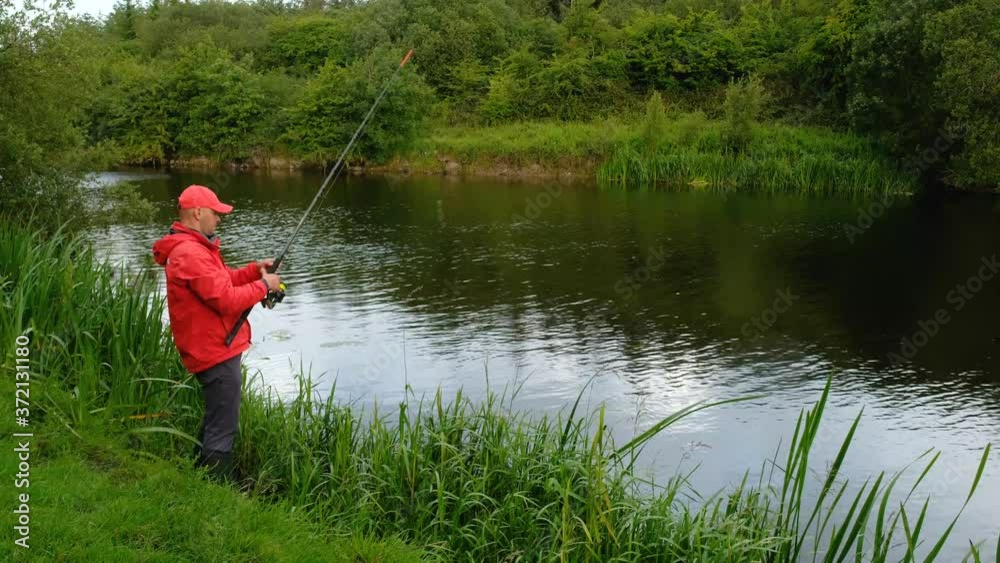 Fisherman on the bank of the river with fishing rod in the hands Fisherman on the bank of the river with fishing rod in the hands