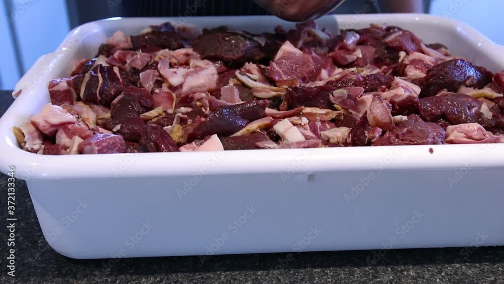 Adding Finely Ground Pepper And Water To Chopped Pork Meat In A Dish Tray For Making Sausages - close up Adding Finely Ground Pepper And Water To Chopped Pork Meat In A Dish Tray For Making Sausages - close up
