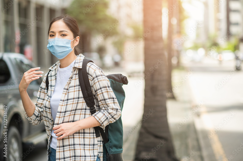 New normal of traveler. Alone young asian beautiful woman travel in holiday with backpack and wearing protection mask virus for safety trip. She walking alone in the city. New normal of traveler. Alone young asian beautiful woman travel in holiday with backpack and wearing protection mask virus for safety trip. She walking alone in the city.