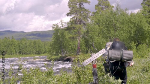 Hikers walking next to a big river along the kings path in Sweden.