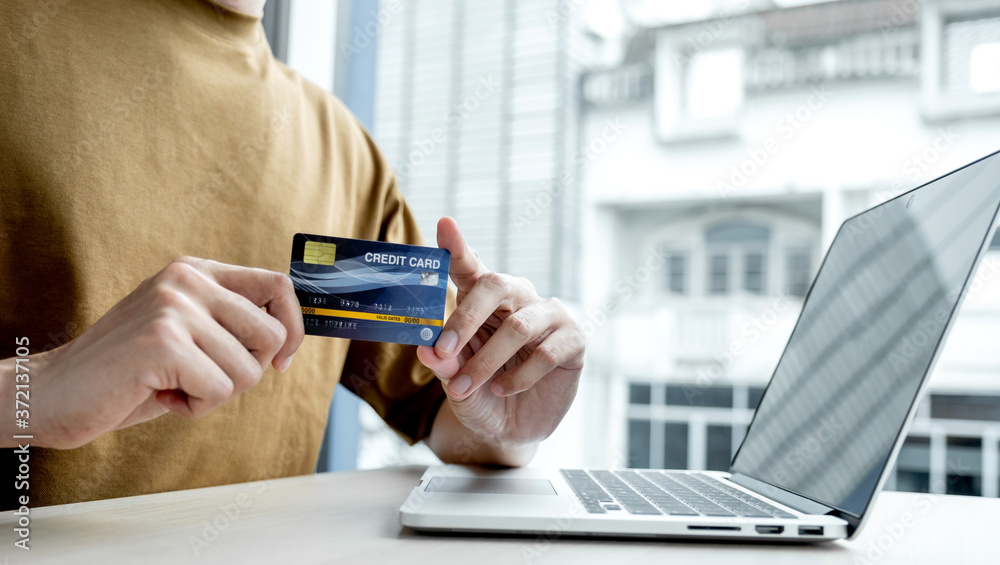 Businessman hand hold credit card to online shopping on laptop computer from home, payment e-commerce, internet banking, spending money Businessman hand hold credit card to online shopping on laptop computer from home, payment e-commerce, internet banking, spending money