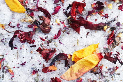 A background image of white sea salt bath salts with dried rose petals and flower buds. 