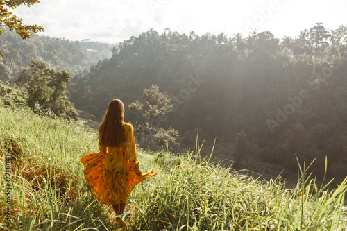 Back view of free Happy Woman Enjoying summer outdoors at Nature with sunlight. Freedom concept in meadow © Yevhenii