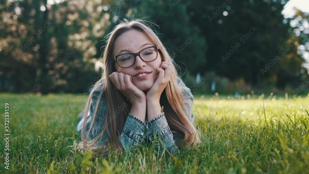 Young caucasian brunette daydreaming while laying on the grass in the park. Relaxation in nature Young caucasian brunette daydreaming while laying on the grass in the park. Relaxation in nature