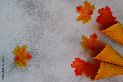 Autumn background orange yellow maple leaves and a waffle cone with space for text