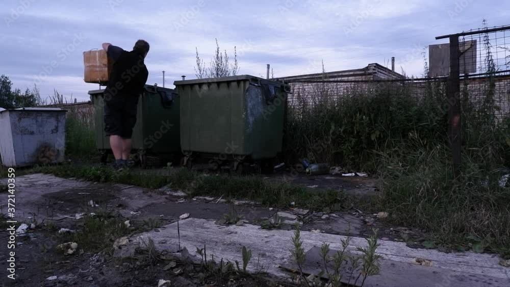 Garage Series. Young man throws unsorted garbage in a regular trash can. Evening light, russia Garage Series. Young man throws unsorted garbage in a regular trash can. Evening light, russia