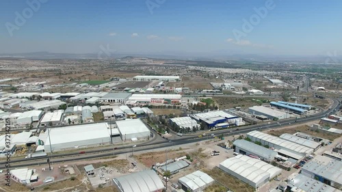 Vista aérea panorámica de la zona industrial de Querétaro. El drone volando hacia atrás con un cielo azul como fondo y cruzando la autopista