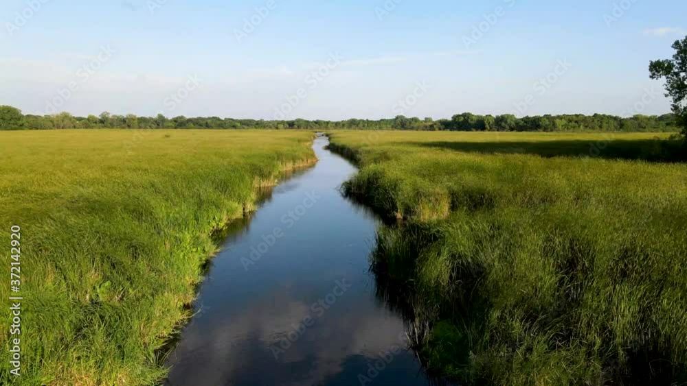 Drone flying forward, following a winding 9 mile creek river in Bloomington Minnesota. Closeup view of calm, still creek winding its way through a thick vegetation. Drone flying forward, following a winding 9 mile creek river in Bloomington Minnesota. Closeup view of calm, still creek winding its way through a thick vegetation.