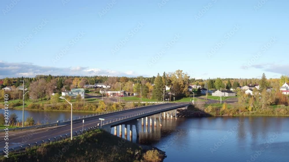 Drone shot over river from bridge into small farming town and farm field Drone shot over river from bridge into small farming town and farm field