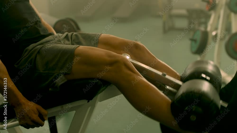 Closeup strong man having legs training at gym. Unrecognizable bodybuilding man making leg extension in sport club. Unknown male athlete workout in fitness center