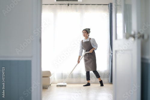 A young maid cleaning the house with a mop