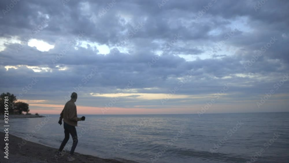 Man Happily Jumps And Stretches By The Beach Overlooking A Wonderful Pink And Purple Sunset - wide shot Man Happily Jumps And Stretches By The Beach Overlooking A Wonderful Pink And Purple Sunset - wide shot