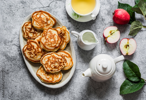 Delicious breakfast, snack - apple pancakes, green tea, fresh apples, cream on a gray background, top view
