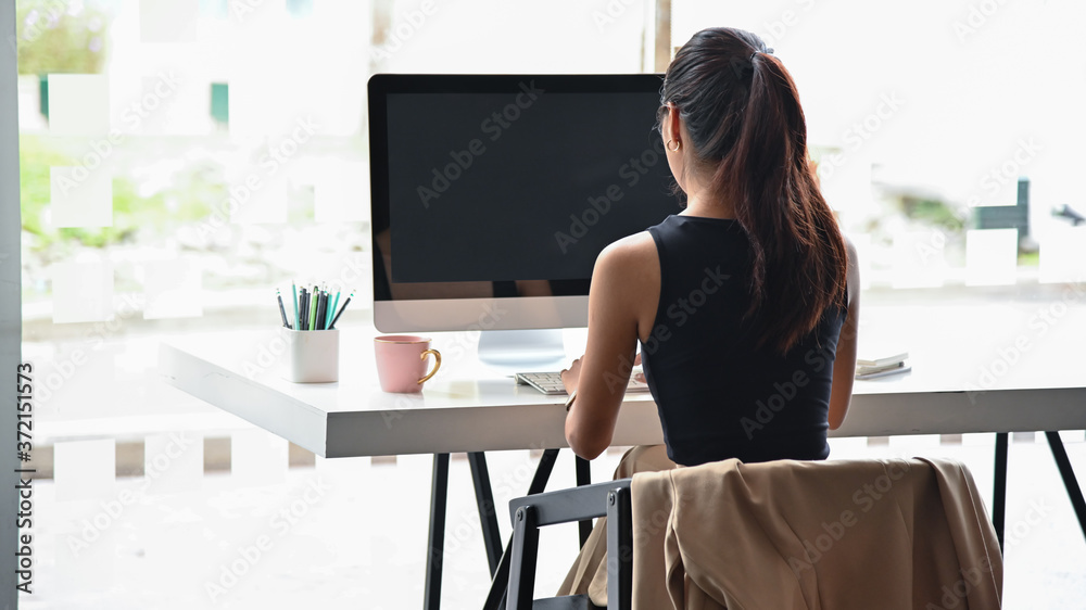Back view of image young business woman working with computer on white table in office. Back view of image young business woman working with computer on white table in office.