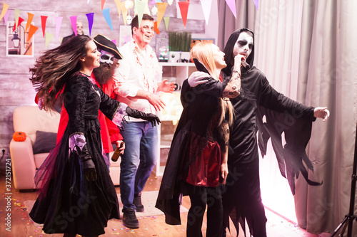 Vampire woman and grim reaper doing karaoke while celebrating halloween.