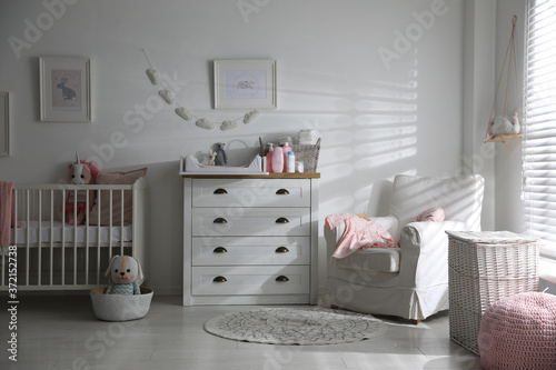 Chest of drawers with changing tray and pad in baby room. Interior design photo