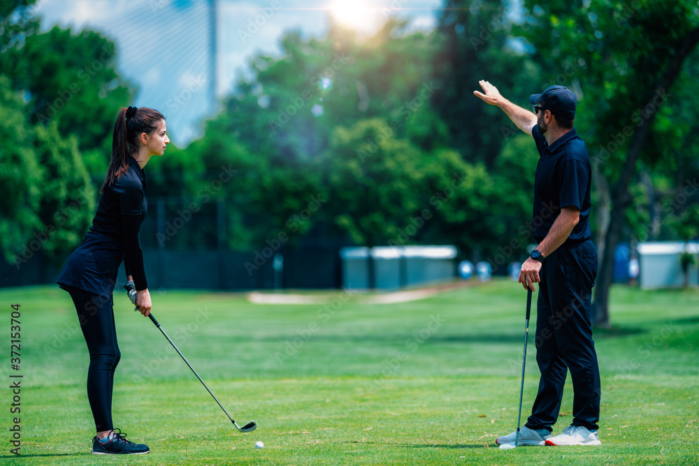 Obraz premium Playing golf. Young woman playing golf with golf instructor