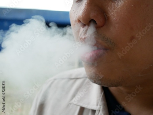 closeup of young asian man smoking cigarette.