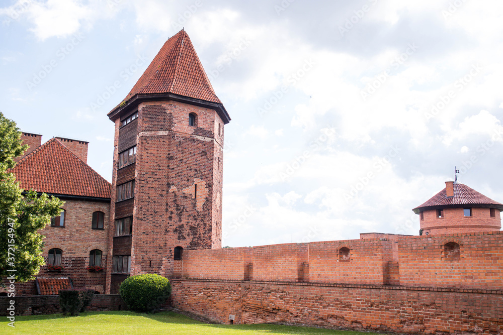 Outside walls of Teutonic Malbork Castle with single tower visible.