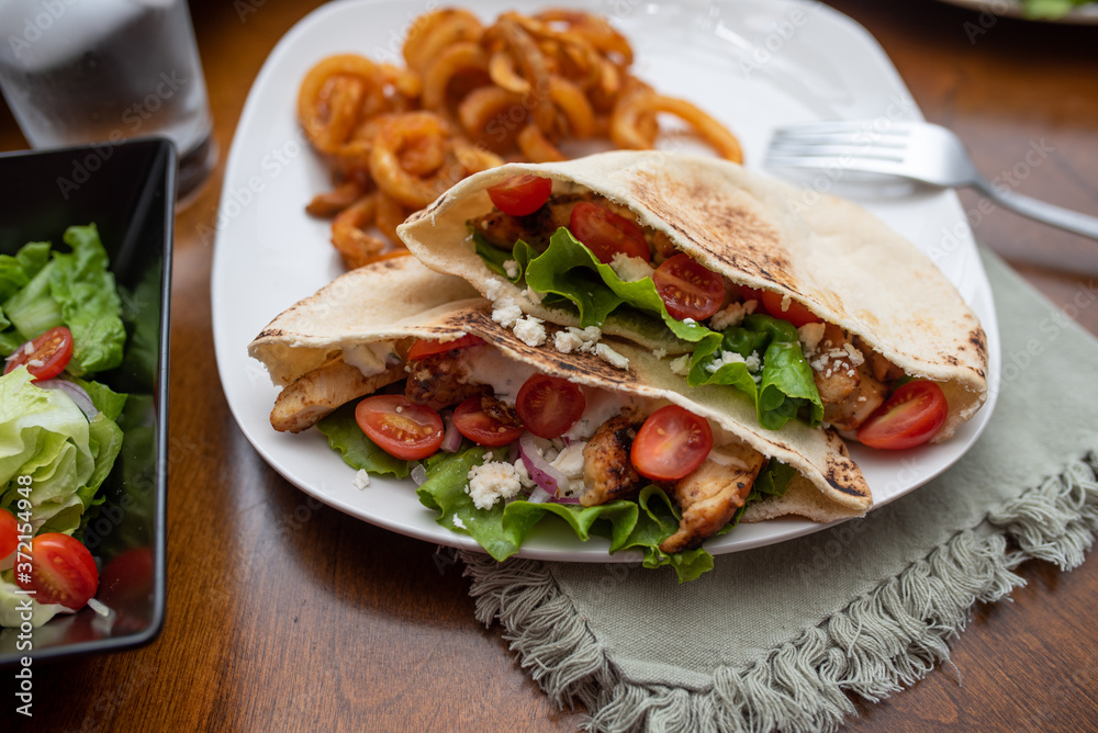 Chicken souvlaki pita with Tzatziki, Greek style sandwich served with salad and curly fries. Chicken souvlaki pita with Tzatziki, Greek style sandwich served with salad and curly fries.