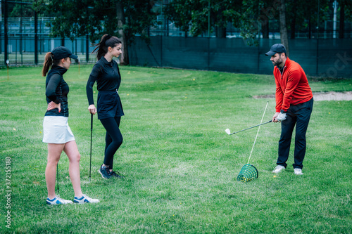 Golf lesson. Golf instructor showing swing technique to young women