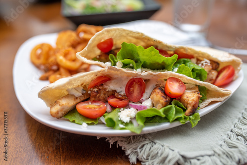 Chicken souvlaki  pita with Tzatziki, Greek style sandwich served with salad and curly fries.  