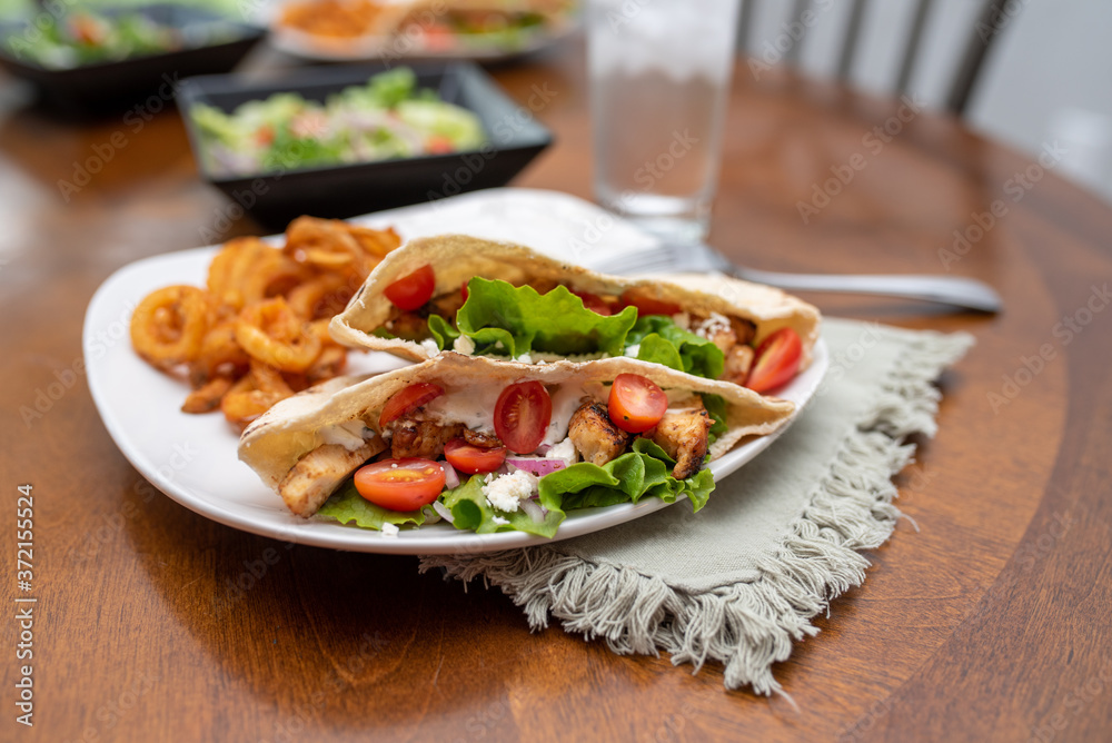 Chicken souvlaki pita with Tzatziki, Greek style sandwich served with salad and curly fries. Chicken souvlaki pita with Tzatziki, Greek style sandwich served with salad and curly fries.