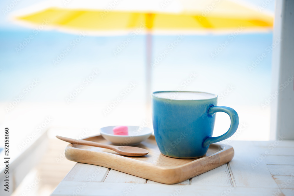 Summer blue coffee Latte cup by the beach  with yellow umbrella background