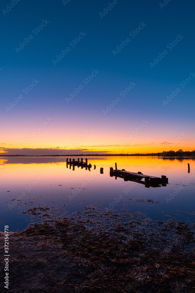 A broken wooden pier on the lake at dawn, Gorokan, Australia.