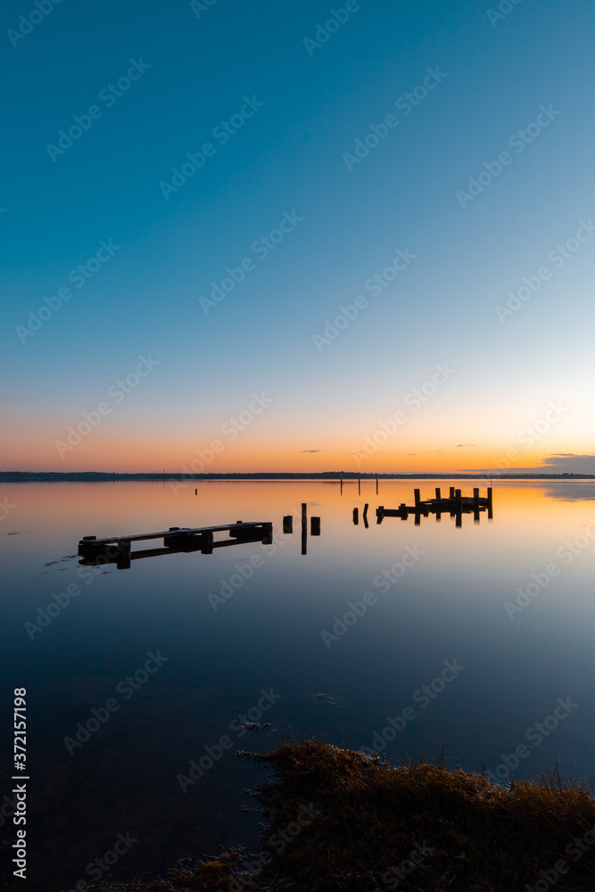 A broken wooden pier on the lake at sunrise time, Gorokan, Australia. A broken wooden pier on the lake at sunrise time, Gorokan, Australia.