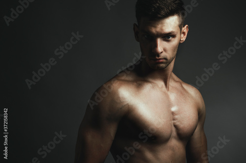 Fitness body concept. Muscular young man posing over gray background. Perfect body. Close up. Studio shot