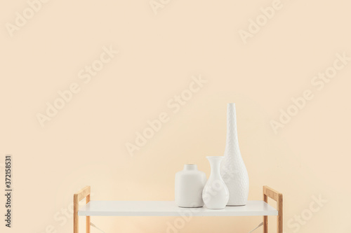 Table with vases in empty room © Pixel-Shot